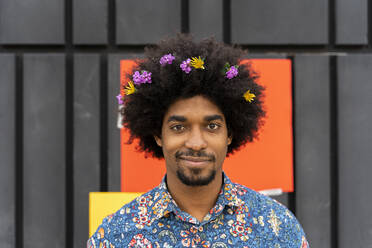 Hispanic bearded male with Afro hairstyle in Hawaiian shirt looking away  thoughtfully while touching hair against ribbed green backdrop stock photo