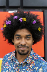 Portrait of man with blossoms in his hair wearing colorful shirt - AFVF03881