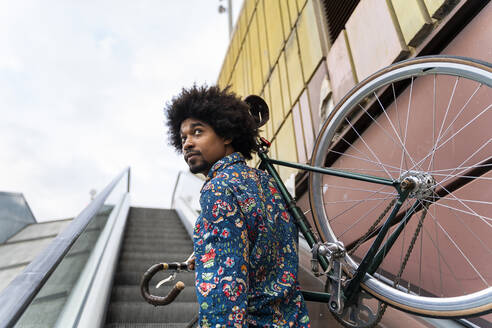 Stilvoller Mann mit Fahrrad auf Rolltreppe - AFVF03885