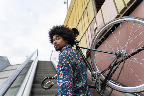 Stylish man carrying bicycle on escalator - AFVF03885