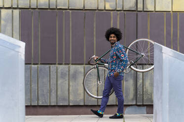 Stylish man carrying bicycle in the city - AFVF03886