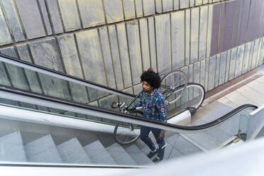 Stylish man carrying bicycle on escalator - AFVF03888