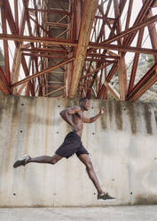 Junger Mann joggt unter einer Brücke - LJF00734