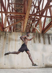 Young man jogging under a bridge - LJF00734