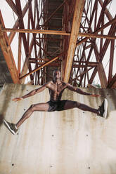 Young man jogging under a bridge - LJF00735