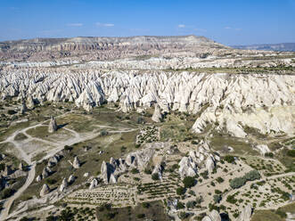 Aerial view of volcanic landscape against blue sky during sunny day at Goreme, Cappadocia, Turkey - KNTF03069