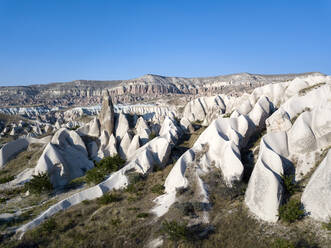 Aerial view of volcanic landscape against clear blue sky in Goreme during sunny day, Cappadocia, Turkey - KNTF03074