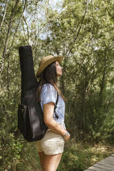 Young woman with guitar case looking up - LJF00744