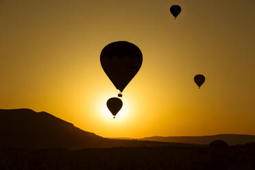 Silhouette Heißluftballons fliegen über Landschaft gegen klaren Himmel in Goreme bei Sonnenuntergang, Kappadokien, Türkei - KNTF03092