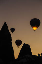 Silhouette hot air balloons flying over mountains at Goreme during sunset, Cappadocia, Turkey - KNTF03093