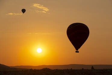 Silhouette Heißluftballons fliegen über Landschaft gegen Himmel bei Sonnenuntergang in Kappadokien, Türkei - KNTF03099