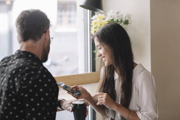 Junges Paar mit Einwegbecher und Smartphone in einem Cafe - ALBF00945