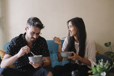 Young couple siiting on a couch in a cafe having breakfast - ALBF00962