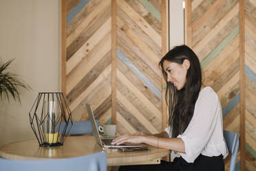 Junge Geschäftsfrau mit Laptop am Tisch in einem Café - ALBF00965