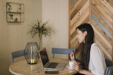 Junge Geschäftsfrau mit Laptop am Tisch in einem Café - ALBF00969