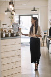 Young woman standing at the counter in a cafe - ALBF00978