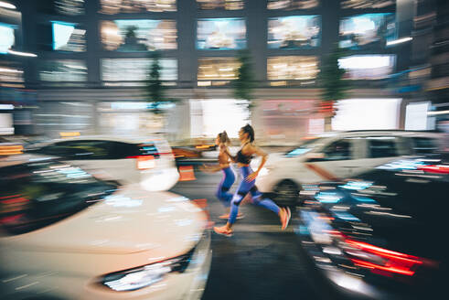 Long exposure photo of two women running through the streets in the city at night - OCMF00592