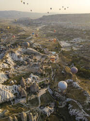 Luftaufnahme von bunten Heißluftballons, die über das Land im Goreme-Nationalpark, Kappadokien, Türkei, fliegen - KNTF03144