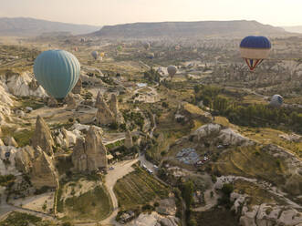 Luftaufnahme von bunten Heißluftballons, die über das Land im Goreme-Nationalpark, Kappadokien, Türkei, fliegen - KNTF03148