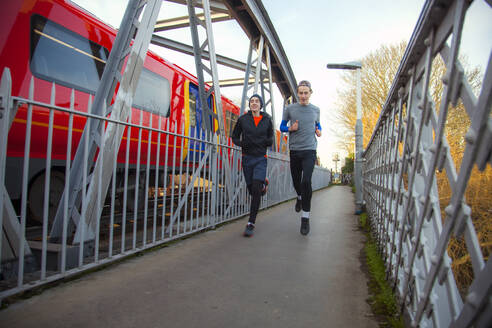 Zwei Teenager rennen über eine Eisenbahnbrücke - AJOF00002