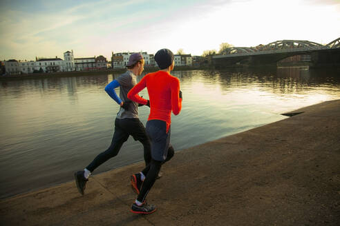 Zwei junge Männer joggen entlang der Themse, London, UK - AJOF00007