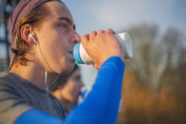 Zwei Teenager trinken Wasser nach einem Lauf - AJOF00011