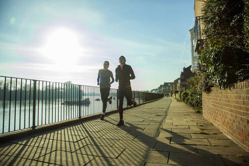 Zwei Teenager joggen entlang der Themse, London, UK - AJOF00014