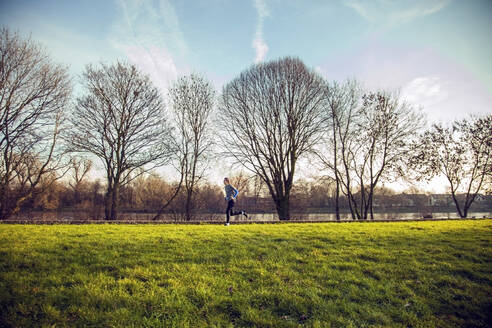 Junger Mann joggt in einem Park - AJOF00017