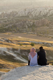 Paar genießt die Aussicht auf die felsige Landschaft in der Abenddämmerung, Goreme, Kappadokien, Türkei - KNTF03171