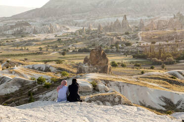 Paar genießt die Aussicht auf die felsige Landschaft in der Abenddämmerung, Goreme, Kappadokien, Türkei - KNTF03172