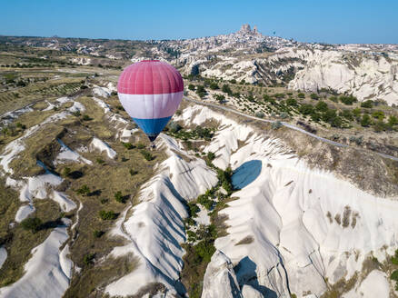 Luftaufnahme eines Heißluftballons, der über Felsformationen im Goreme-Nationalpark, Kappadokien, Türkei, fliegt - KNTF03217