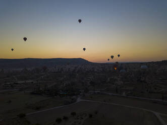 Silhouette Heißluftballons fliegen über Landschaft gegen klaren Himmel bei Sonnenuntergang, Kappadokien, Türkei - KNTF03219