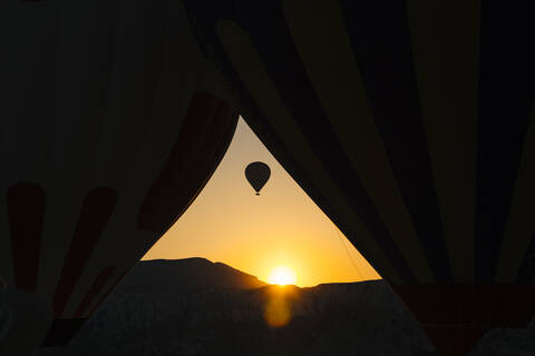 Silhouette Heißluftballon fliegen gegen klaren Himmel durch Zelt während des Sonnenuntergangs gesehen, Kappadokien, Türkei, lizenzfreies Stockfoto