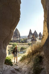 Young woman entering in cave at Goreme village, Cappadocia, Turkey - KNTF03256