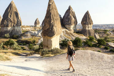 Young woman with backpack walking on land at Goreme village, Cappadocia, Turkey - KNTF03257