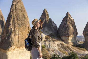 Side view of young woman shielding eyes while standing at Goreme village, Cappadocia, Turkey - KNTF03258