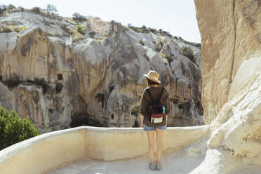 Rear view of tourist with backpack looking at rock formations in Goreme, Cappadocia, Turkey - KNTF03263