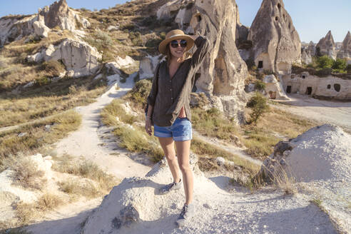 Junge Frau mit Sonnenbrille steht an Land vor Felsformationen in Goreme, Kappadokien, Türkei - KNTF03267