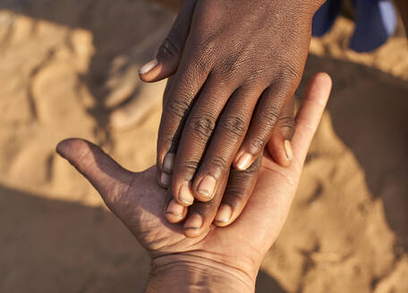 Schwarze Hände schütteln weiße Hände, Stamm der Mucubal, Tchitundo Hulo, Angola - VEGF00542