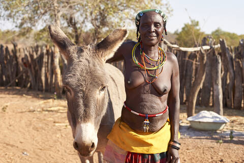 Traditionelle Frau vom Stamm der Mudimba und ihr Esel, Canhimei, Angola, lizenzfreies Stockfoto