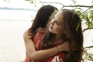 Teenage girls embarcing on beach - AMEF00063