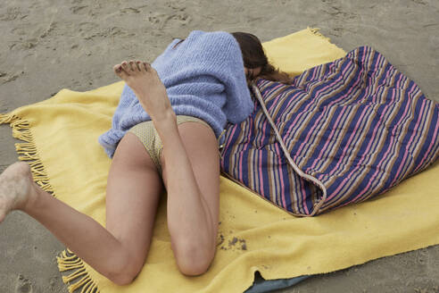 Teenager-Mädchen liegt auf einer Decke am Strand - AMEF00065