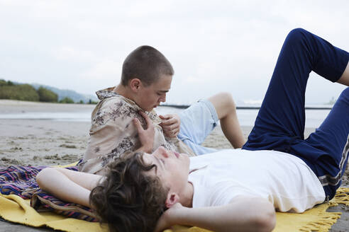 Freunde entspannen sich am Strand, träumen, liegen auf einer Decke - AMEF00070