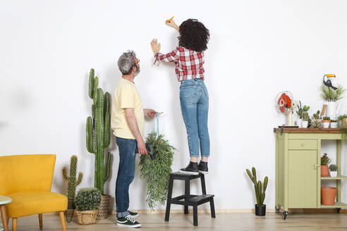 Paar hängt Pflanze an die Wand zu Hause - RTBF01344