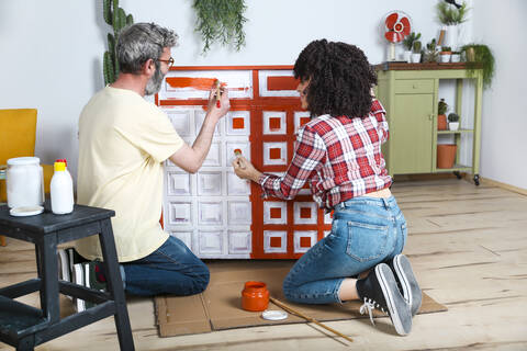 Couple painting furniture with brush at home stock photo