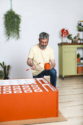Mann malt Möbel mit Pinsel zu Hause - RTBF01357
