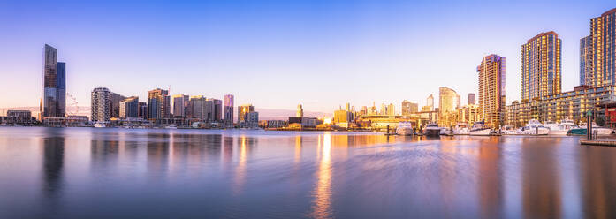 Modern buildings in front of Yarra River at Melbourne Docklands against sky at sunset, Victoria, Australia - SMAF01415