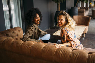 Multicultural women sitting on a sofa in a cafe - MPPF00010