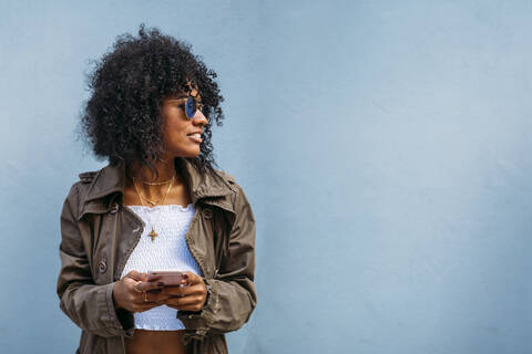 Frau mit Smartphone, blauer Hintergrund, lizenzfreies Stockfoto