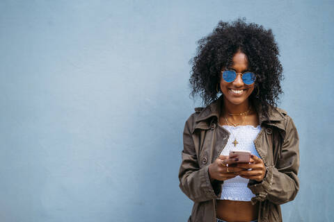 Frau mit Smartphone, blauer Hintergrund, lizenzfreies Stockfoto